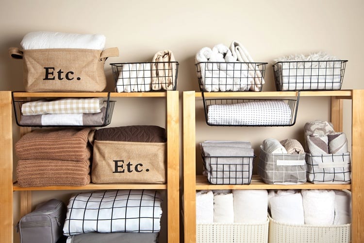 Bedroom shelves with folded blankets, towels, and labeled baskets for organized storage.