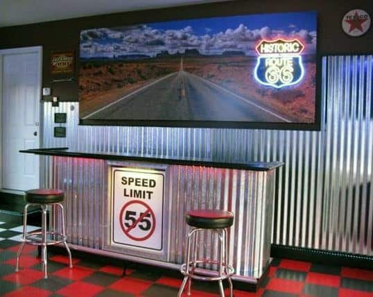 Route 66-themed garage bar with corrugated metal design, neon sign, and retro stools.