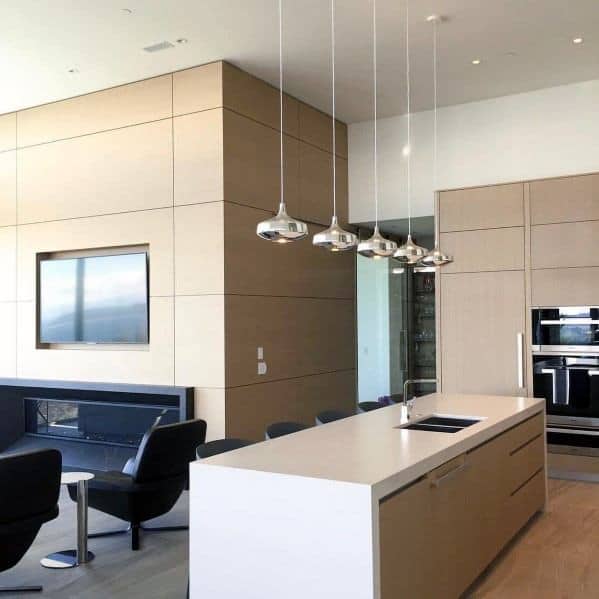 Contemporary kitchen with metallic chrome small pendant lights hanging above a minimalist white island, complemented by sleek cabinetry and modern furnishings