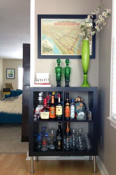 Modern black shelf mini bar with bottles, glassware, and green accents.