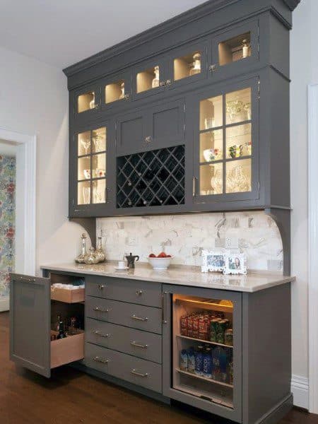 Elegant mini bar with gray cabinetry, built-in wine rack, glass display, and marble backsplash.