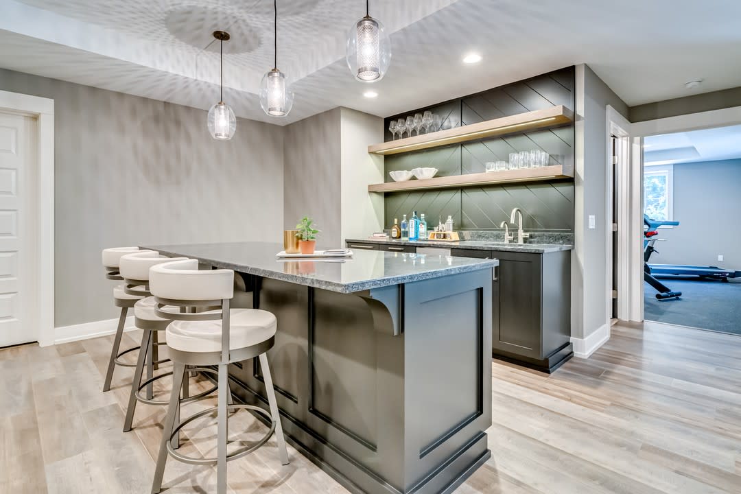 Large modern basement kitchen with island seating, pendant lights, and open shelving.