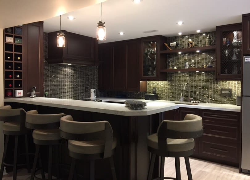 A sophisticated modern kitchen featuring rich dark wood cabinetry, sleek bar seating, and ambient lighting for a warm, inviting atmosphere.