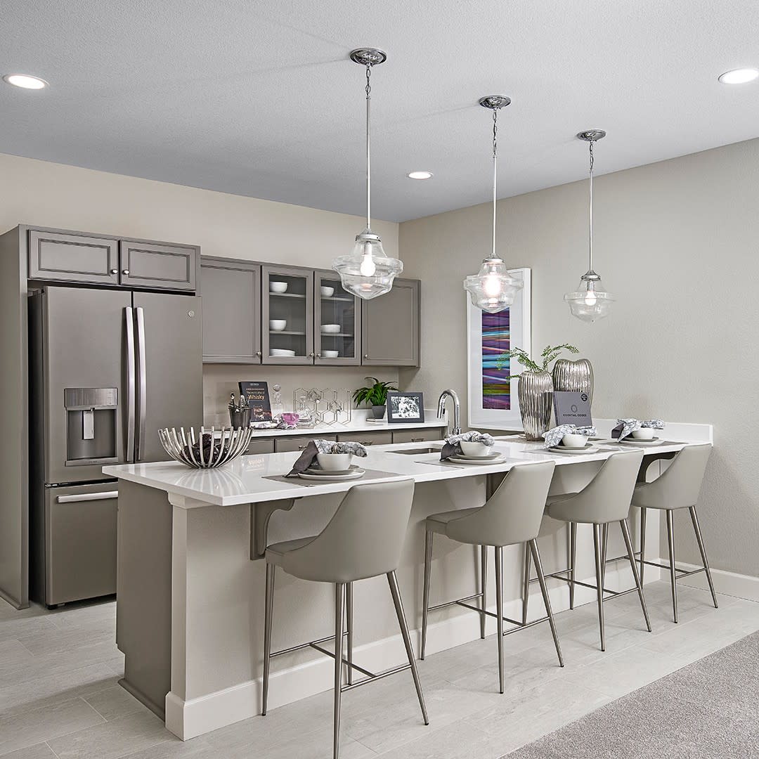 A sleek kitchen with low-hanging pendant lights, a spacious island, and chic bar seating for a modern dining experience.