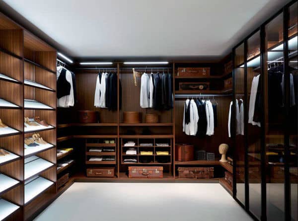 Spacious, modern walk-in closet with wooden shelves, hanging clothes, shoes, and luggage