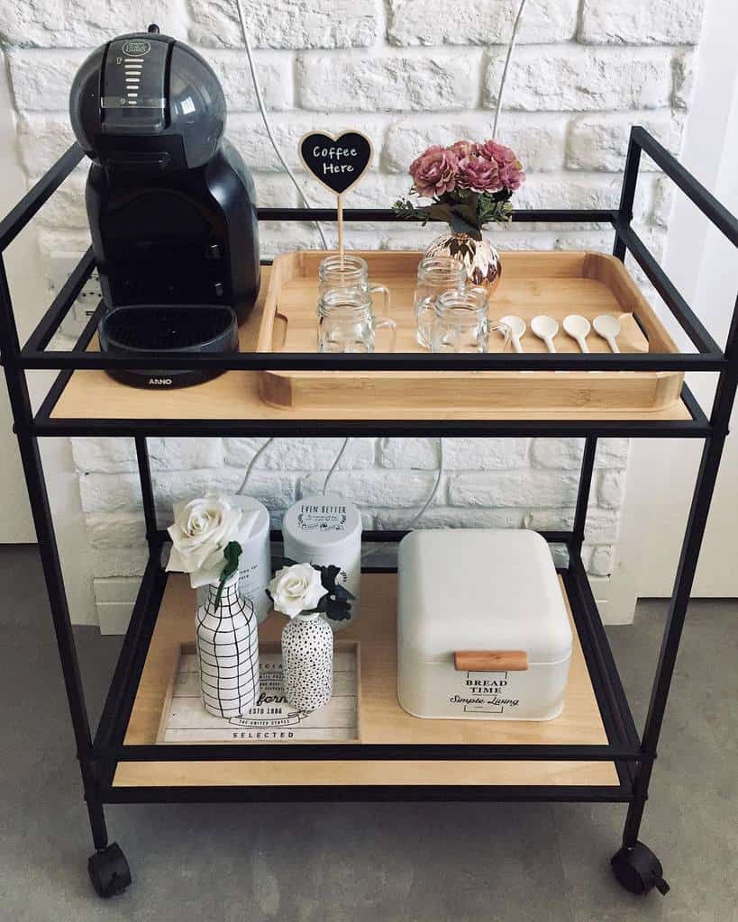 Modern coffee bar cart with a coffee machine, jars, spoons, and decorative vases, styled for a cozy bed and breakfast setting.