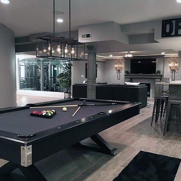 Modern game room with pool table, bar stools, open layout, and chic lighting fixtures.