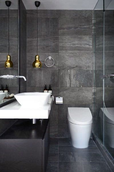 Modern bathroom with grey tiles, white fixtures, and golden pendant lights