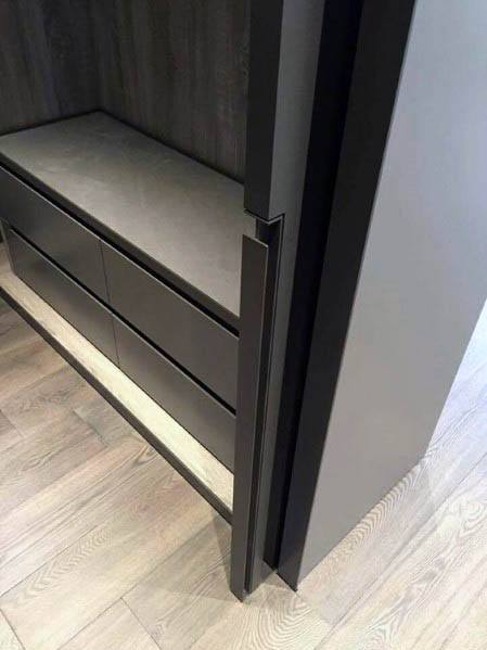 Sleek black pocket door design in a modern closet featuring built-in storage drawers, matte finishes, and light wood flooring