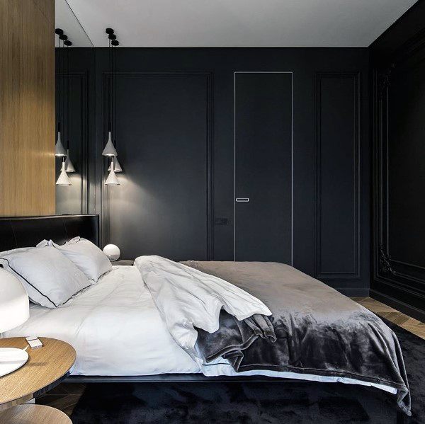 Modern black bedroom with paneled walls, cozy bedding, and sleek pendant lighting.