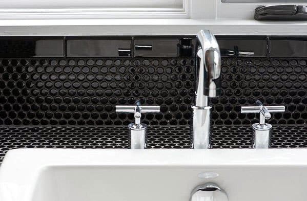 Black circular tile backsplash with chrome faucet and white sink in modern bathroom.