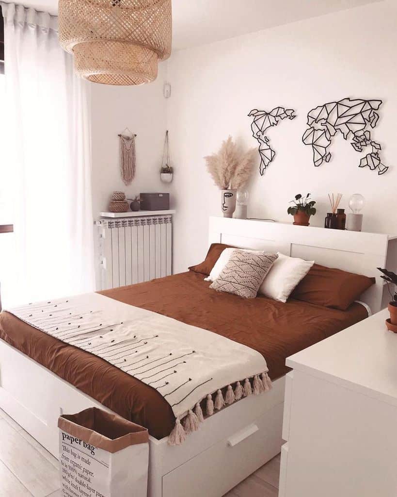 Modern boho bedroom with earthy tones, wicker lighting, abstract wall art, and pampas grass decor.