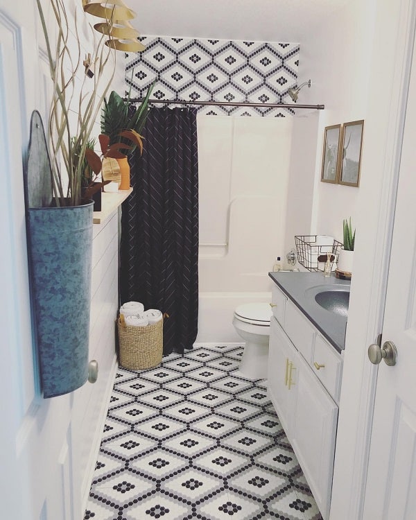 Boho farmhouse bathroom with patterned tile floor, black shower curtain, and white vanity.