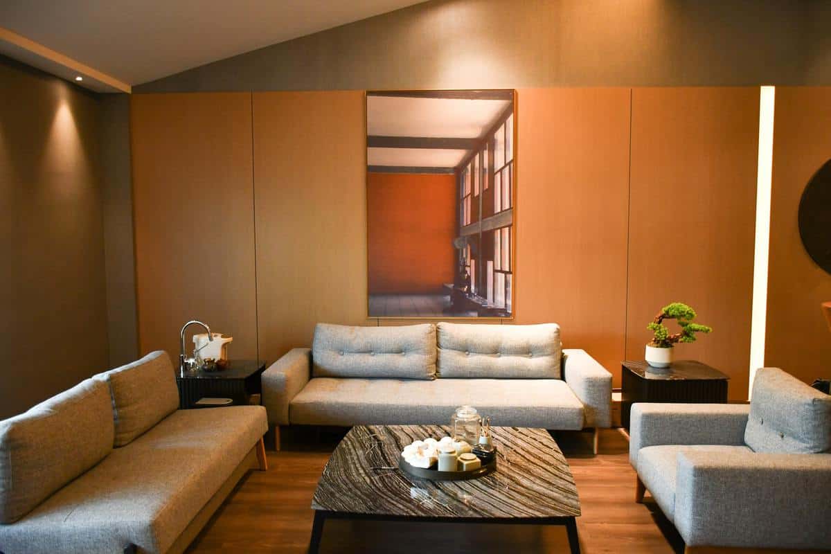 Modern living room with gray sofas, a brown wooden coffee table adorned with candles, and a large wall painting