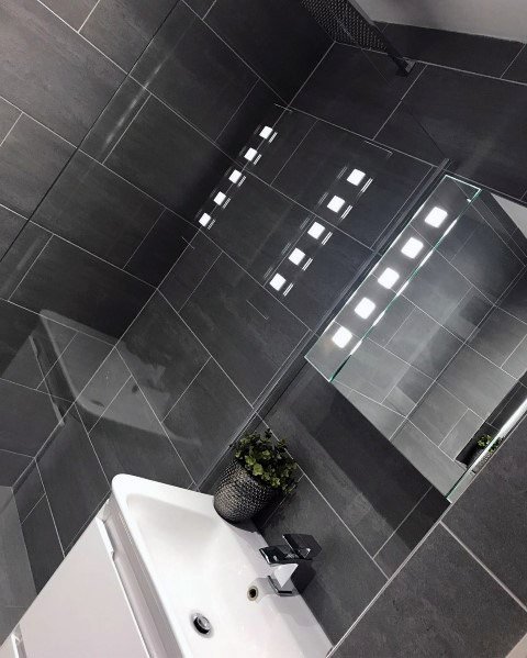 Modern bathroom with grey tiles, mirror, white sink, and a potted plant