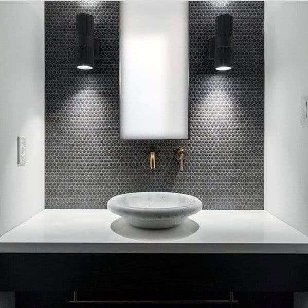 Bathroom with dark grey mosaic tile backsplash, vessel sink, and wall-mounted lights.