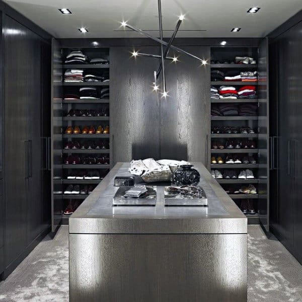 Modern walk-in closet with dark wood shelves, an island, clothes, shoes, and a starburst chandelier