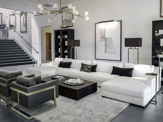 Contemporary living room with a white sectional sofa, black and white decor, geometric art, and stylish lighting