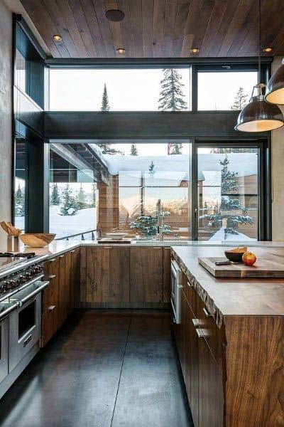 Rustic-modern kitchen featuring wooden cabinets, a wood-paneled ceiling, and expansive windows with a snowy mountain view.