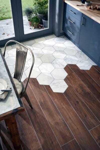 A stylish kitchen with hexagonal marble tiles blending into rich hardwood, complemented by blue cabinetry and natural light