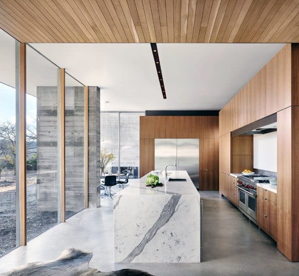 Modern kitchen featuring a marble island, warm wood cabinetry, and large floor-to-ceiling windows.