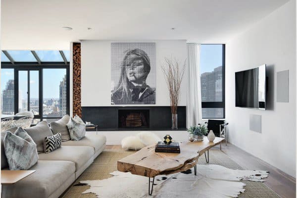 Modern living room with a spacious sofa, wooden coffee table, fireplace, and city view through floor-to-ceiling windows