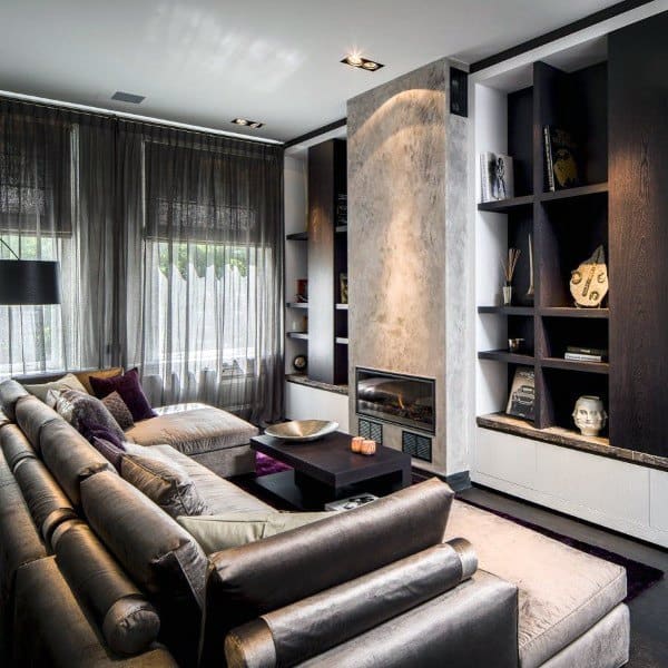 Modern living room with gray sofas, built-in shelves, a fireplace, and large windows draped with sheer curtains