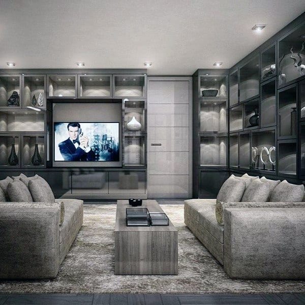 Modern living room with gray sofas, a large TV, and sleek shelves displaying decor pieces