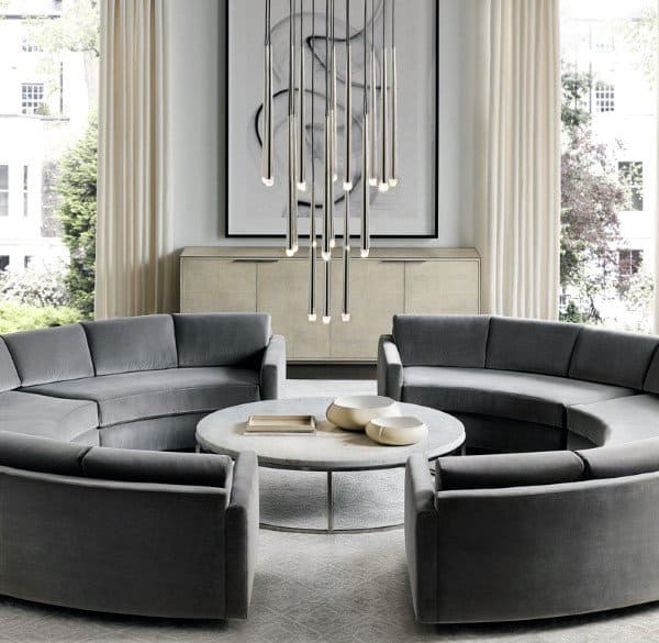 Chic living room with gray circular sofas, a round coffee table, large artwork, and a sleek vertical light fixture