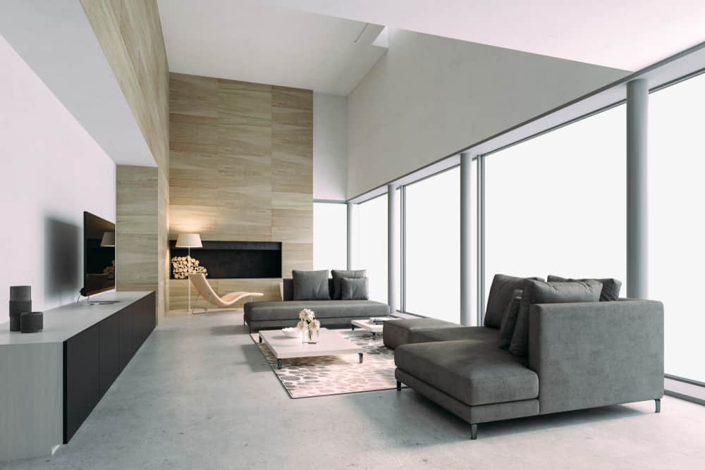 Spacious modern living room with gray sofas, wood-paneled accent wall, large windows, and sleek minimalist decor