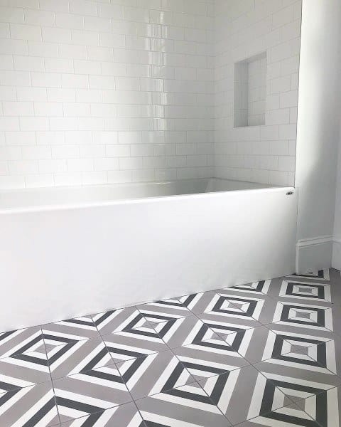 Modern bathroom with black, white, and gray geometric patterned floor tiles and white subway tile wall.