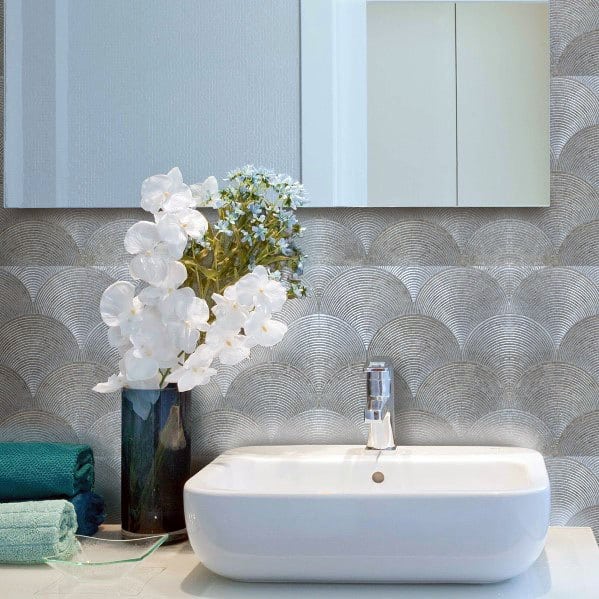 Bathroom with metallic decorative backsplash, white vessel sink, and floral decor.