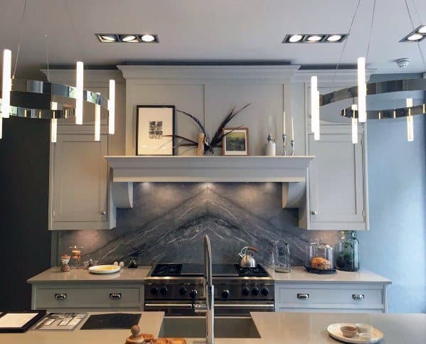 Modern kitchen featuring round polished nickel chandeliers above the island, complemented by a sleek gray color scheme and contemporary design elements