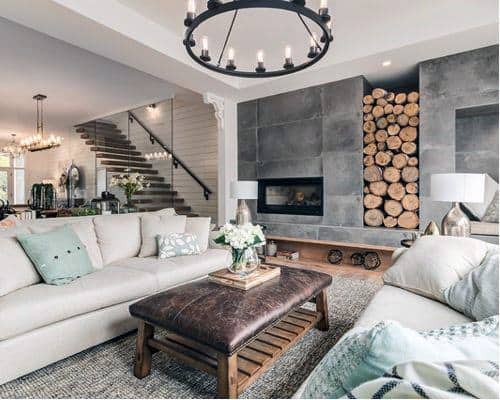 A modern rustic living room featuring a sleek fireplace with stacked logs, comfortable sofas, and stylish lighting, creating a cozy yet contemporary space