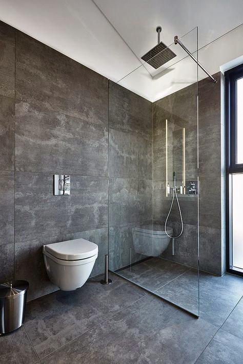 Minimalist bathroom with dark gray tiles, glass shower enclosure, and ceiling-mounted showerhead.