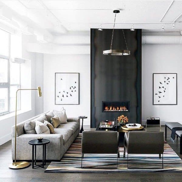 Modern living room with a gray sofa, black fireplace, striped rug, and artworks on white walls