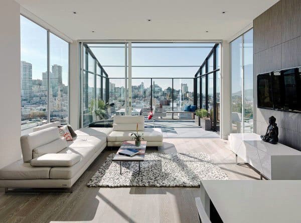 Contemporary living room with white sofas, large windows, city view, and a balcony