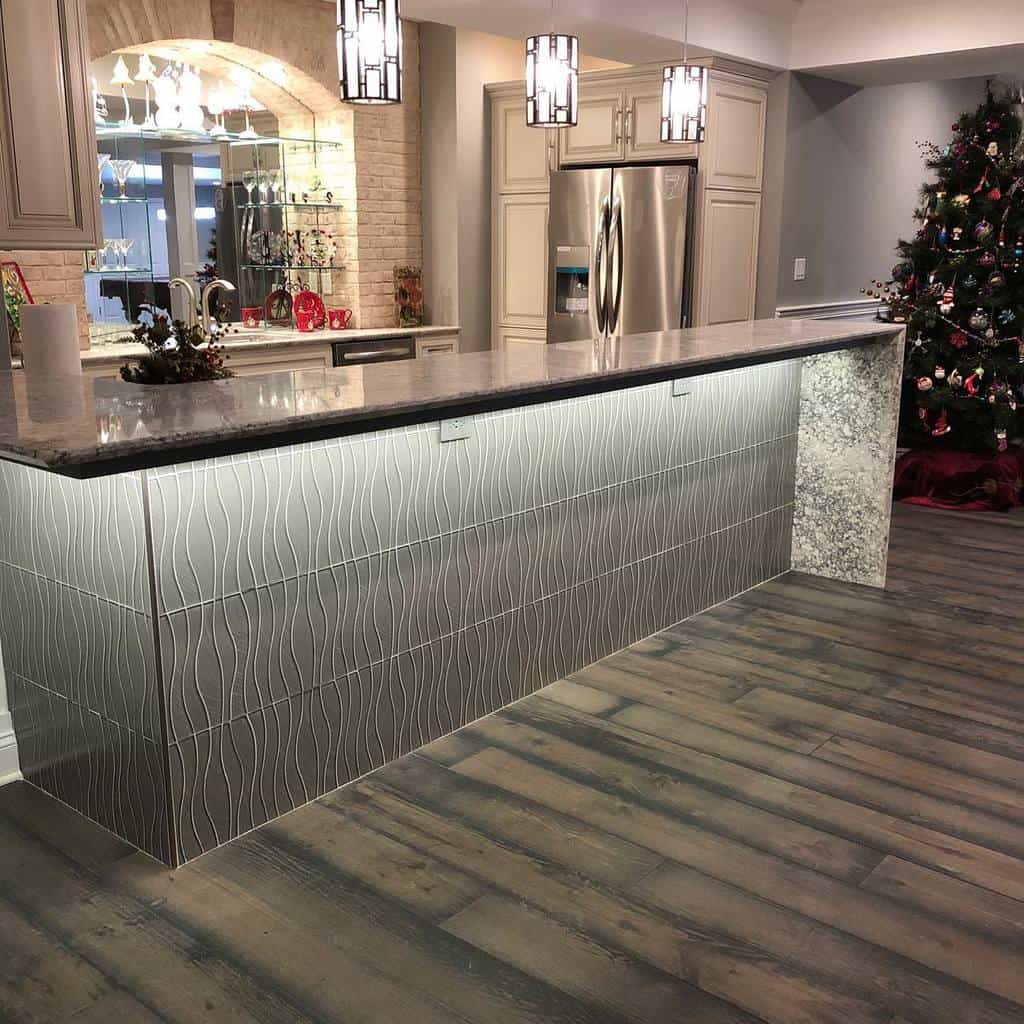 Modern wet bar with illuminated tile front, granite countertop, pendant lights, and festive decor.