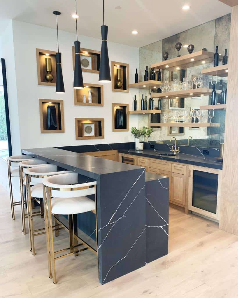 Luxury wet bar with black marble countertops, gold accents, open shelving, and pendant lighting.