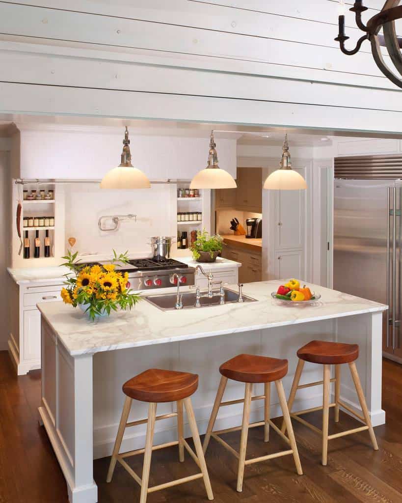 Bright kitchen island with marble countertop, wooden stools, pendant lighting, and fresh decor.