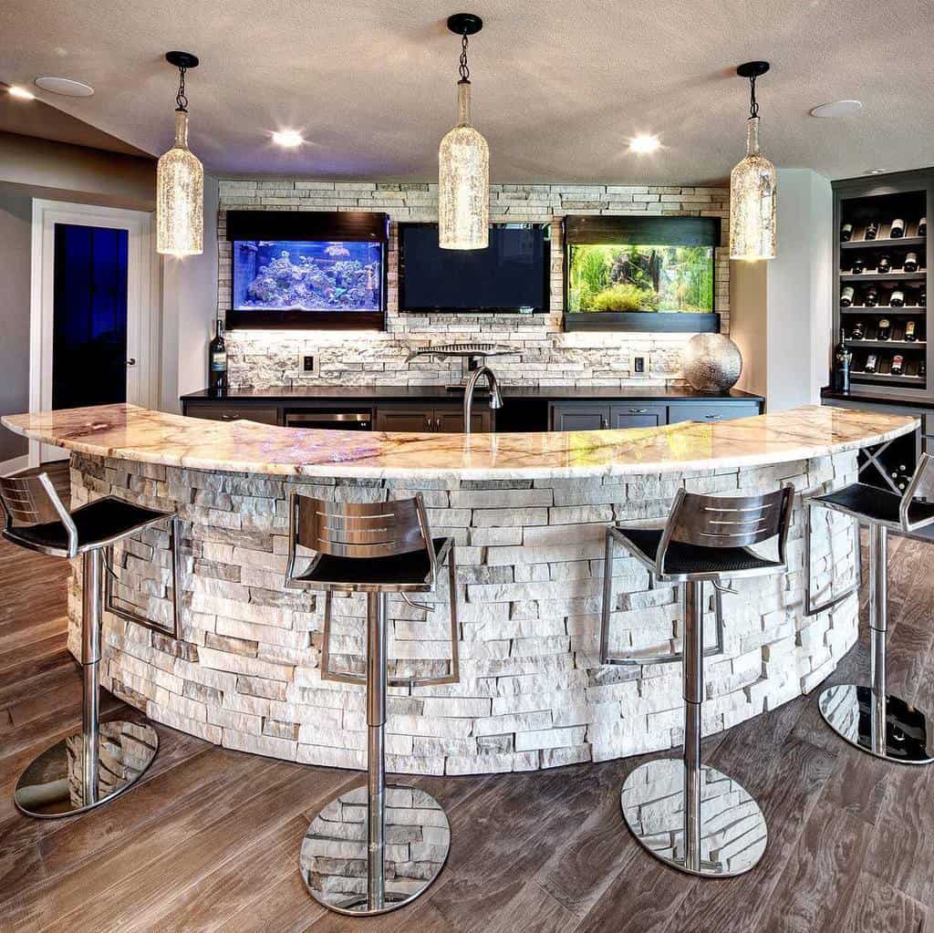 Contemporary wet bar with curved stone facade, granite countertop, pendant lights, and aquariums.