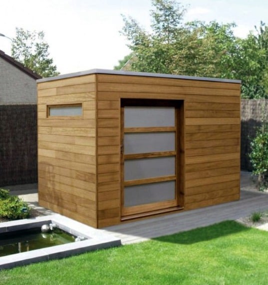 Compact wooden box-style shed with frosted glass door, located in a landscaped backyard