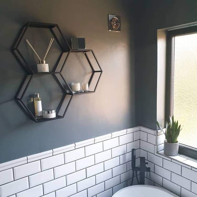 Bathroom with black hexagonal wall shelves, dark gray walls, and white subway tiles.