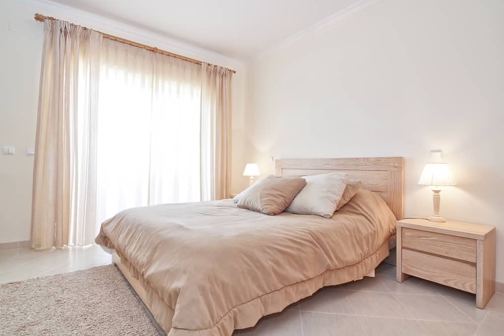 Minimalist bedroom with neutral tones, soft lighting, and simple wooden furniture.