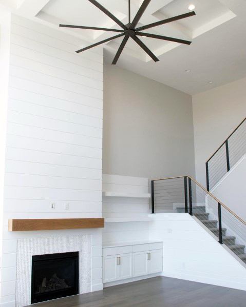 A minimalist fireplace design featuring mosaic white tiles, a wooden mantel, and sleek modern interiors.