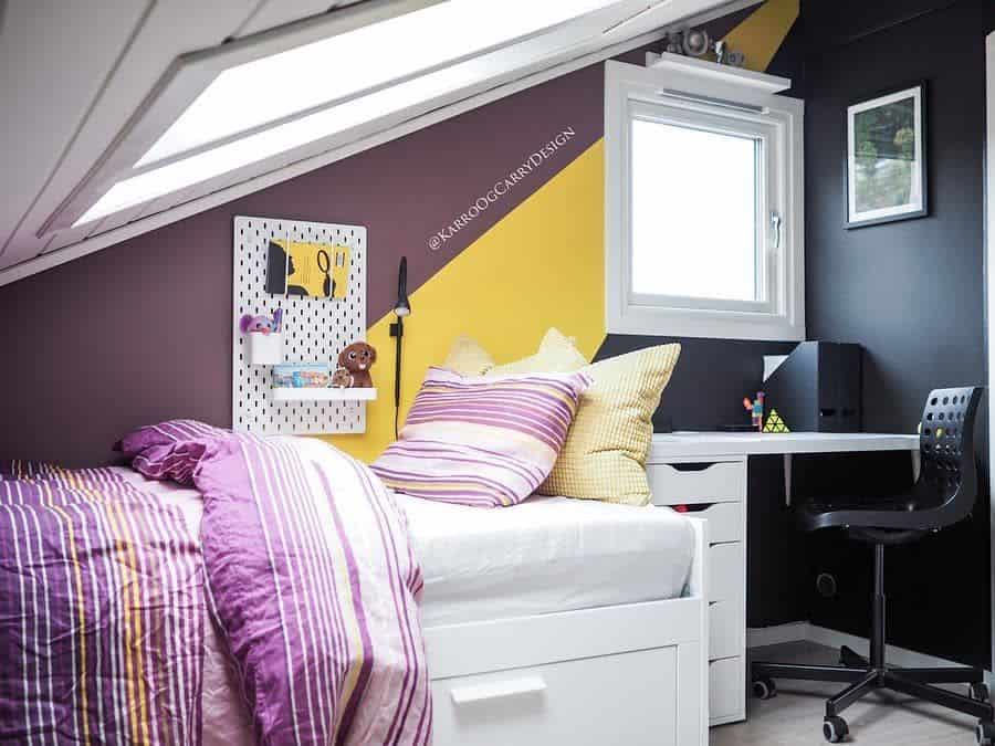 Small attic bedroom with white bed, desk, and yellow accent wall.