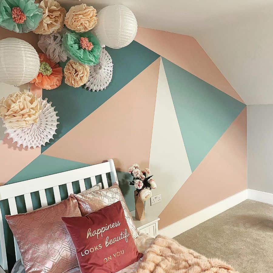 Small single bedroom with green, white, and beige geometric feature wall and decorative accents.