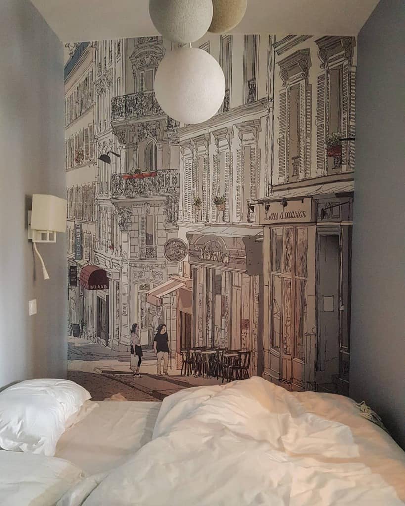 Bedroom with street mural wallpaper, cozy bedding, and pendant globe lights.