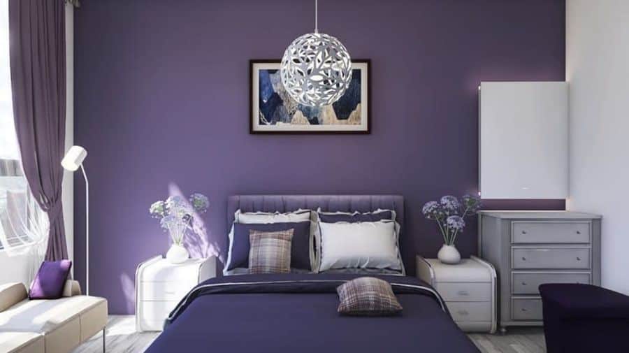 Purple bedroom with tufted bed, white bedside tables, and floral pendant light.