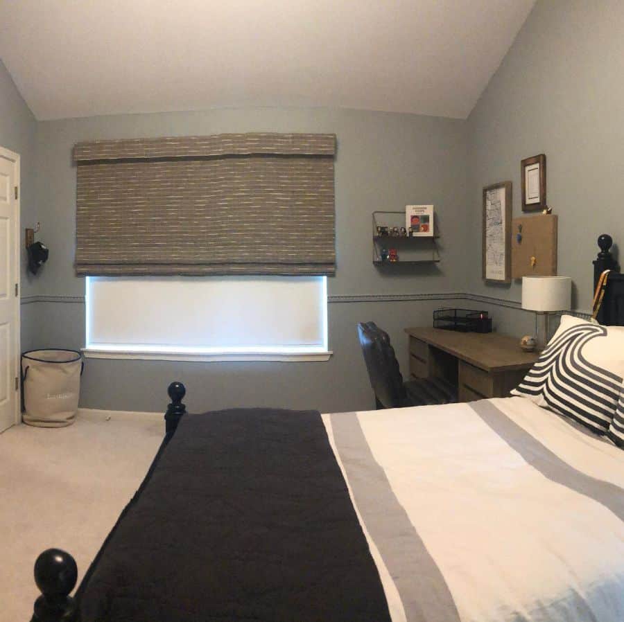 Modern bedroom with gray walls, brown desk, and striped bedding.